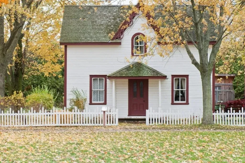 White two-story house with picket fence in autumn