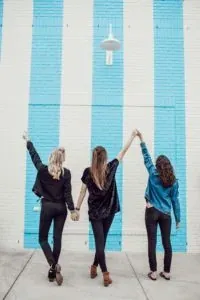 Three women posing by striped wall