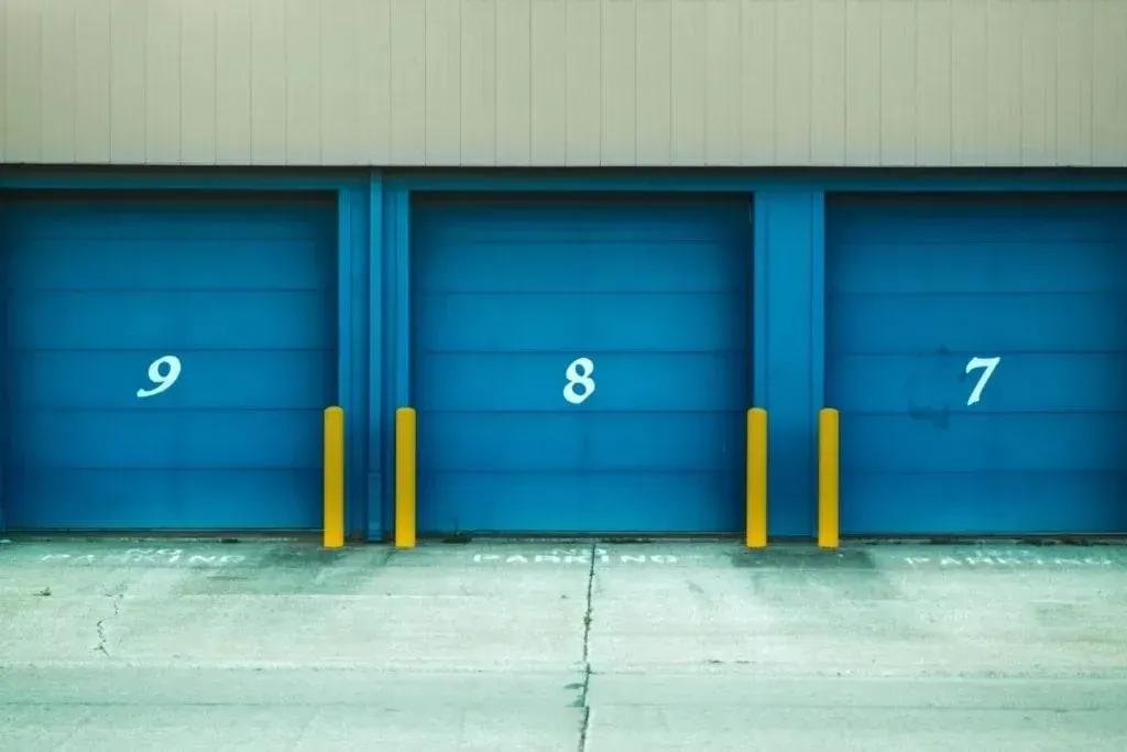 Numbered blue garage doors with yellow bollards