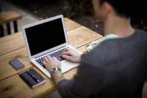 Man typing on laptop outdoors