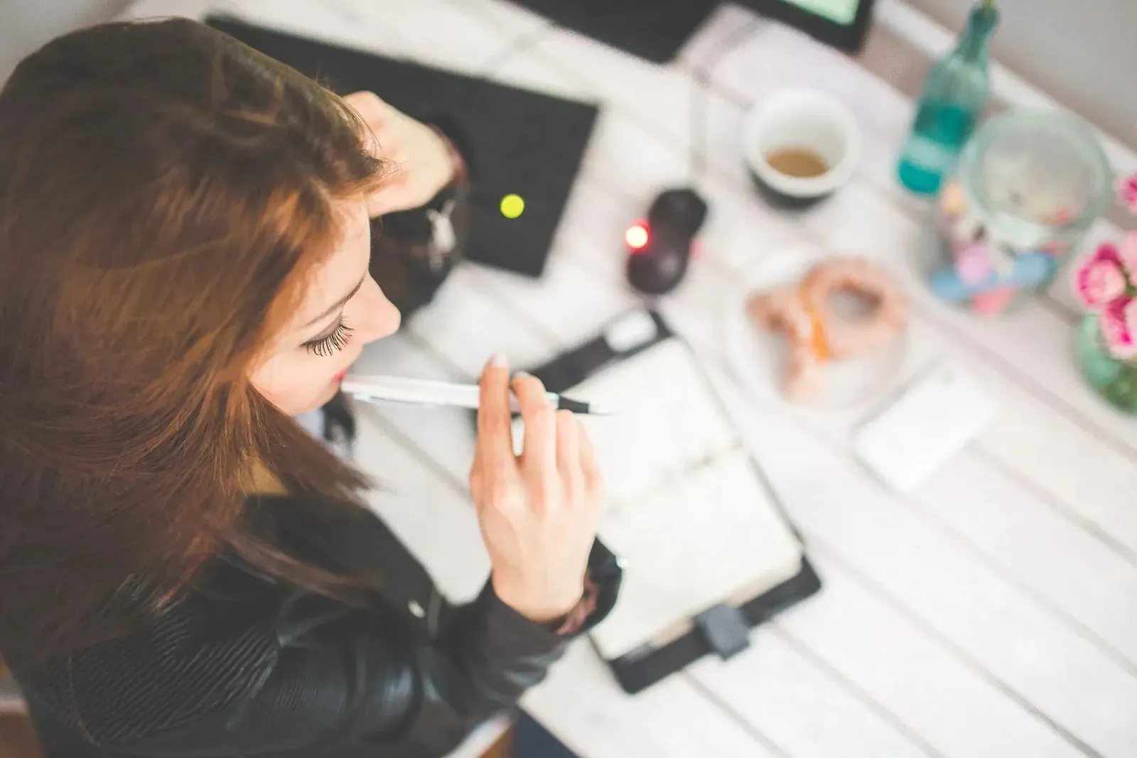 Woman with pen pondering over planner at desk