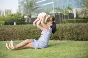 Mother lifting baby on lawn