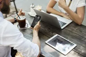 People with phone laptop at table
