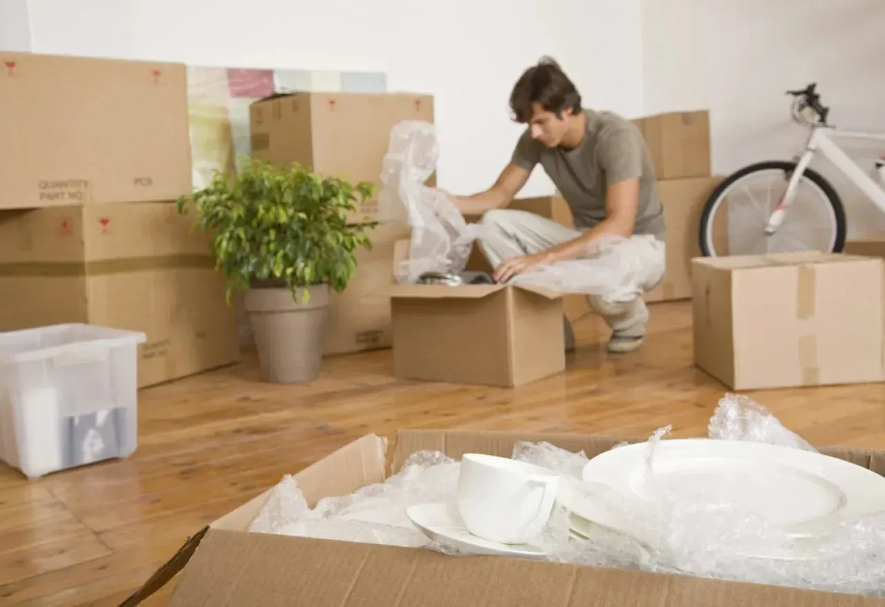 Man unpacking dishes from cardboard boxes in new home