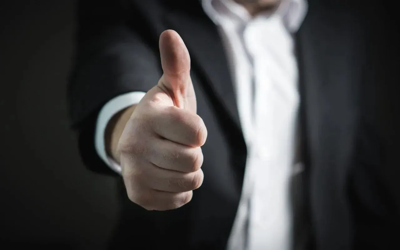 Businessman in dark suit giving thumbs-up gesture