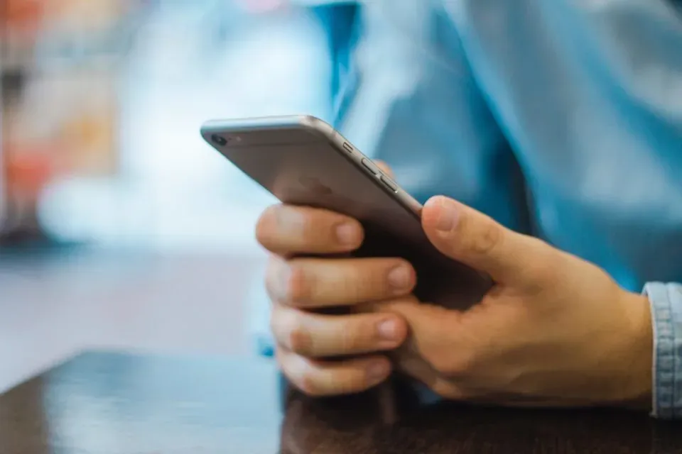 Hands using iPhone at table