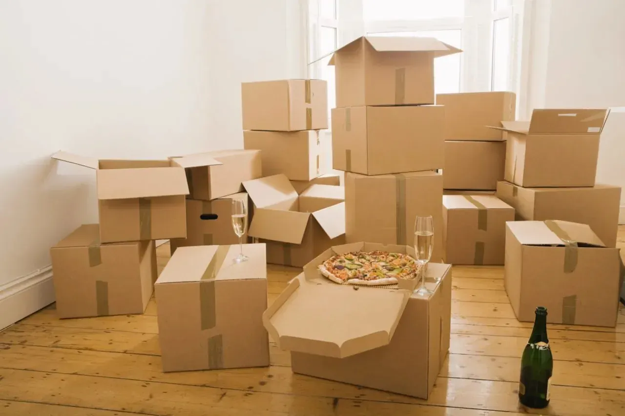 Stacked moving boxes with pizza and champagne