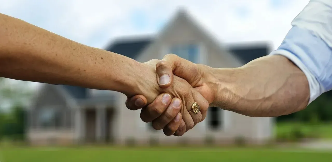 Handshake in front of blurred new house