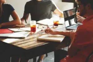 Friends around table with laptop, drinks