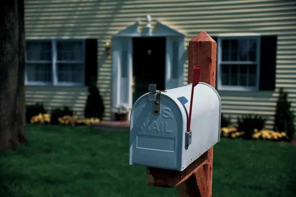White US Mail mailbox in front of suburban house