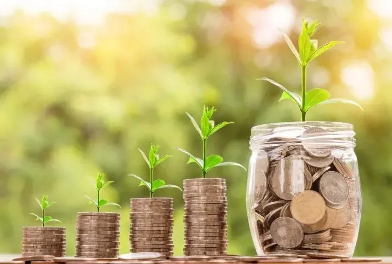 Growing coin stacks with sprouting plants, savings jar
