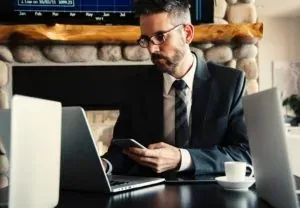 Man in suit with phone and laptops