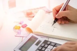 Hand writing notes beside calculator