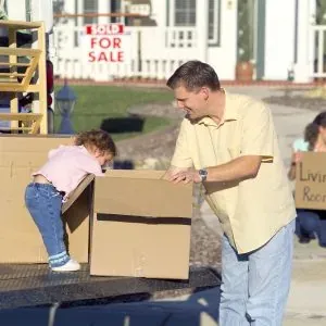 Father and toddler with boxes, sold sign