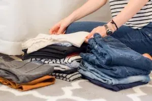 Woman folding stacked clothes on floor