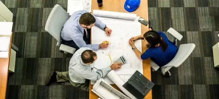 Three colleagues reviewing blueprints at office table