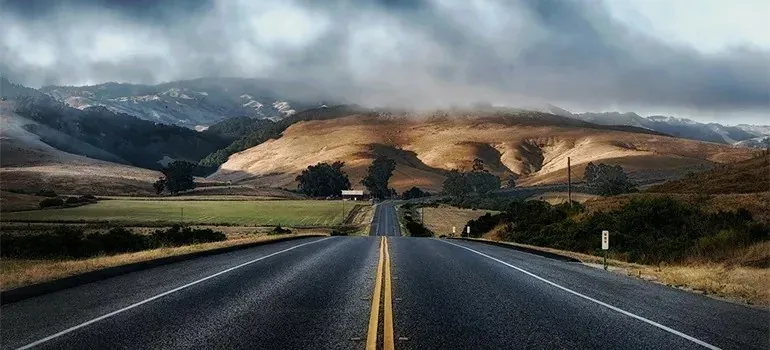 Empty highway leading toward golden California hills