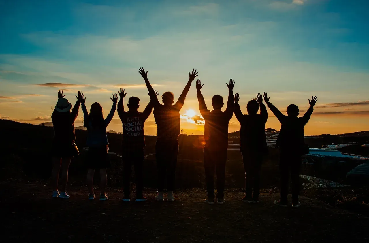Silhouetted group raising arms at sunset