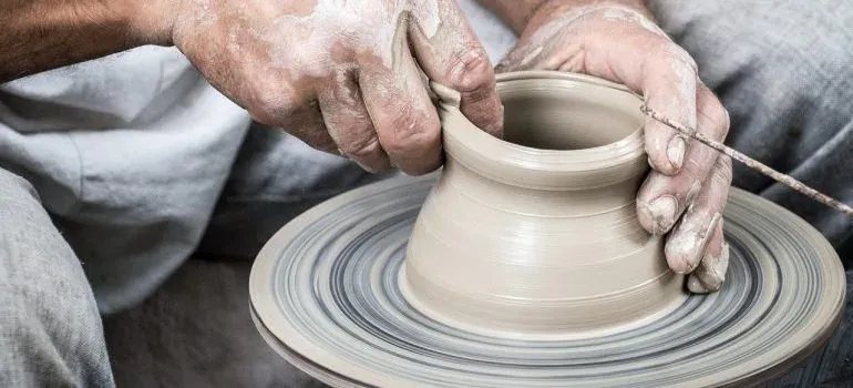 Hands shaping clay on pottery wheel