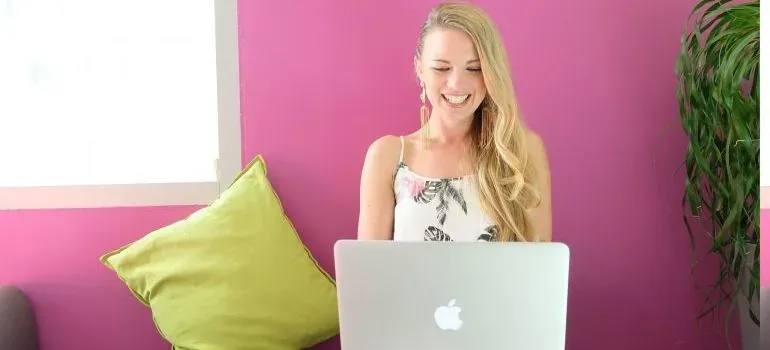 Woman at laptop, pink wall