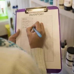 Hand writing inventory list on clipboard