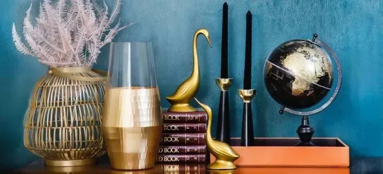 Gold decorative figurines, candles, books and globe on shelf
