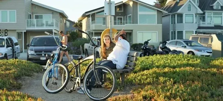 Couple on bench with bicycles near coastal beach houses