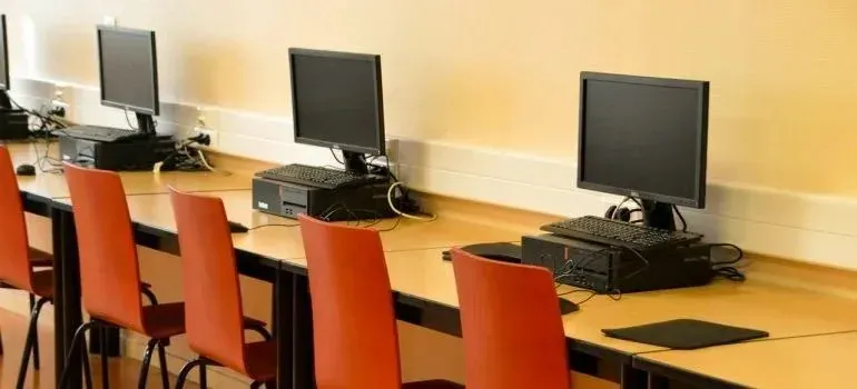Computer lab desks with monitors and red chairs