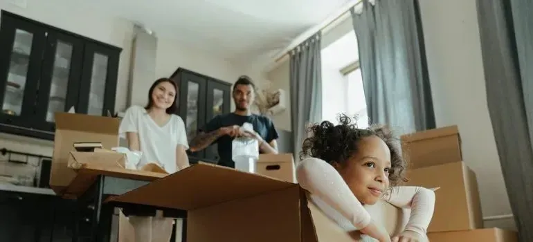 Family unpacking, child playing inside cardboard moving box