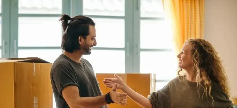 Man and woman shaking hands beside moving boxes