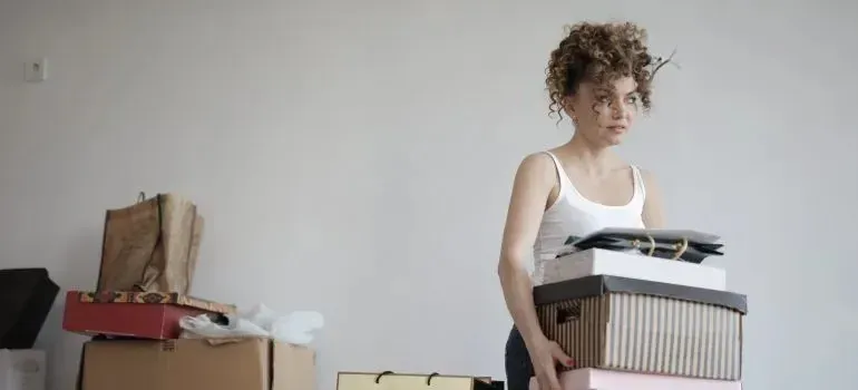 Woman carrying stack of storage boxes in bare room