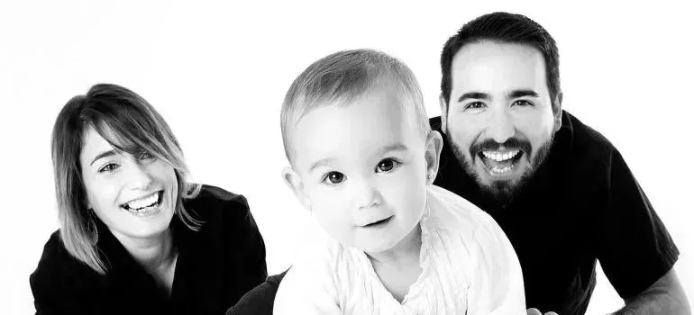Black-and-white studio portrait of parents with baby