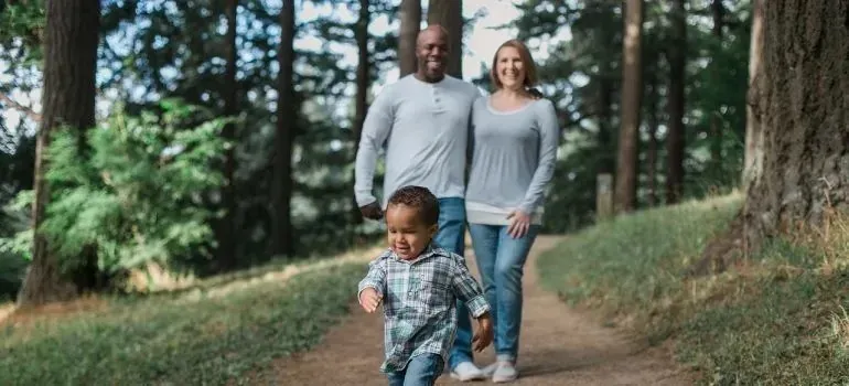 Parents and toddler walking along forest trail