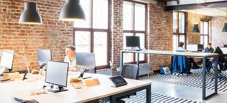 Open-plan brick loft office with workers at monitors