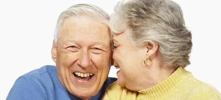 Cheerful senior couple laughing, white studio portrait
