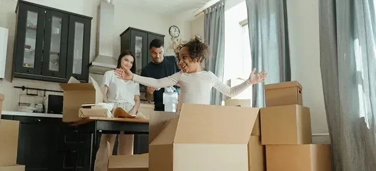 Happy family with child unpacking cardboard boxes in kitchen