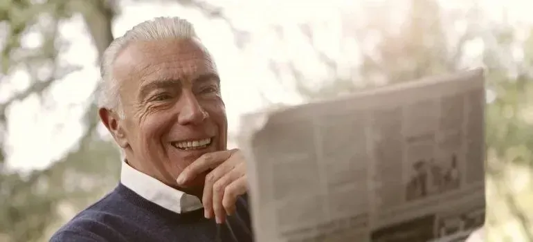 Smiling senior man reading a newspaper outdoors