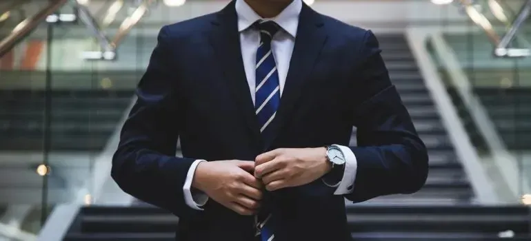 Businessman in navy suit adjusting jacket near staircase