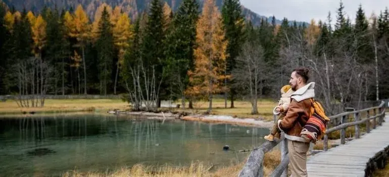 Father holding child beside autumn mountain lake