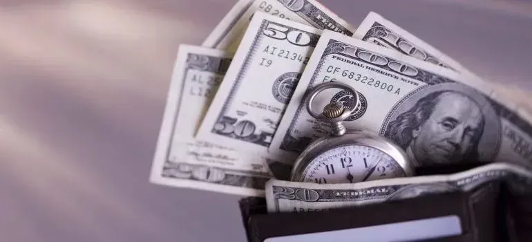 Wallet stuffed with dollar bills and pocket watch