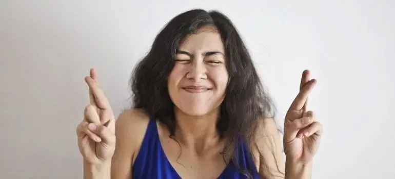 Hopeful woman crossing fingers with eyes closed