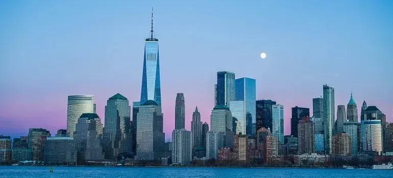 Lower Manhattan skyline at dusk with moon