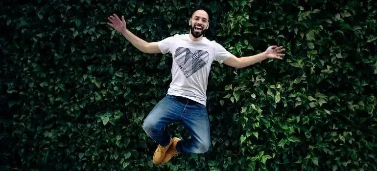 Joyful man jumping in front of ivy-covered wall