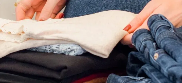 Hands folding clothes and jeans