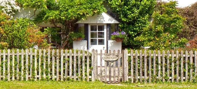 Cottage behind picket fence, Toms Plot sign