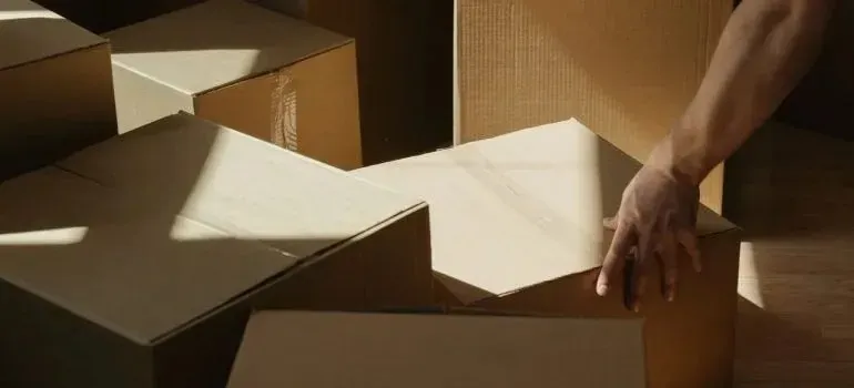 Arm reaching over stacked plain cardboard moving boxes
