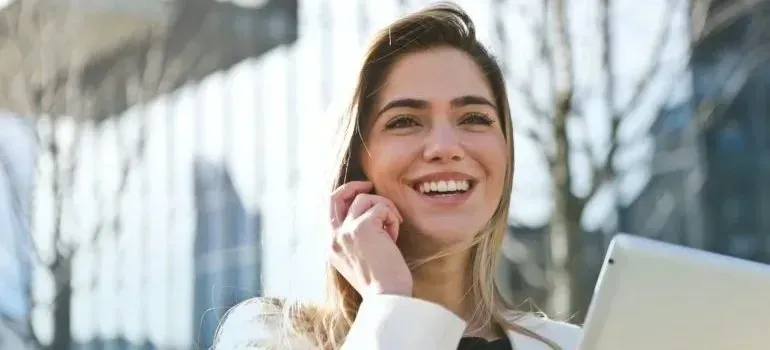 Smiling woman talking on phone outside office buildings