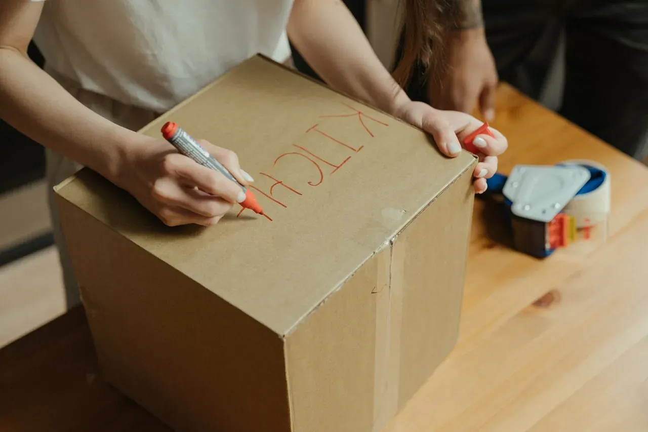 Woman writing KITCHEN on box