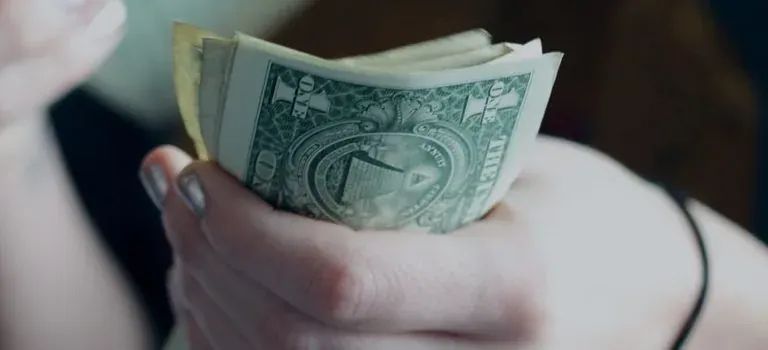 Hands holding folded dollar bills
