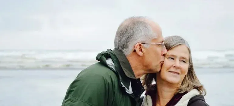 Elderly couple embracing on overcast beach